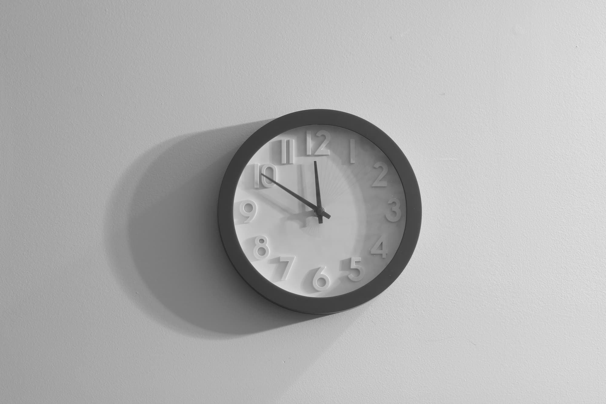 A white wall with a black and white analog wall clock mounted on it.